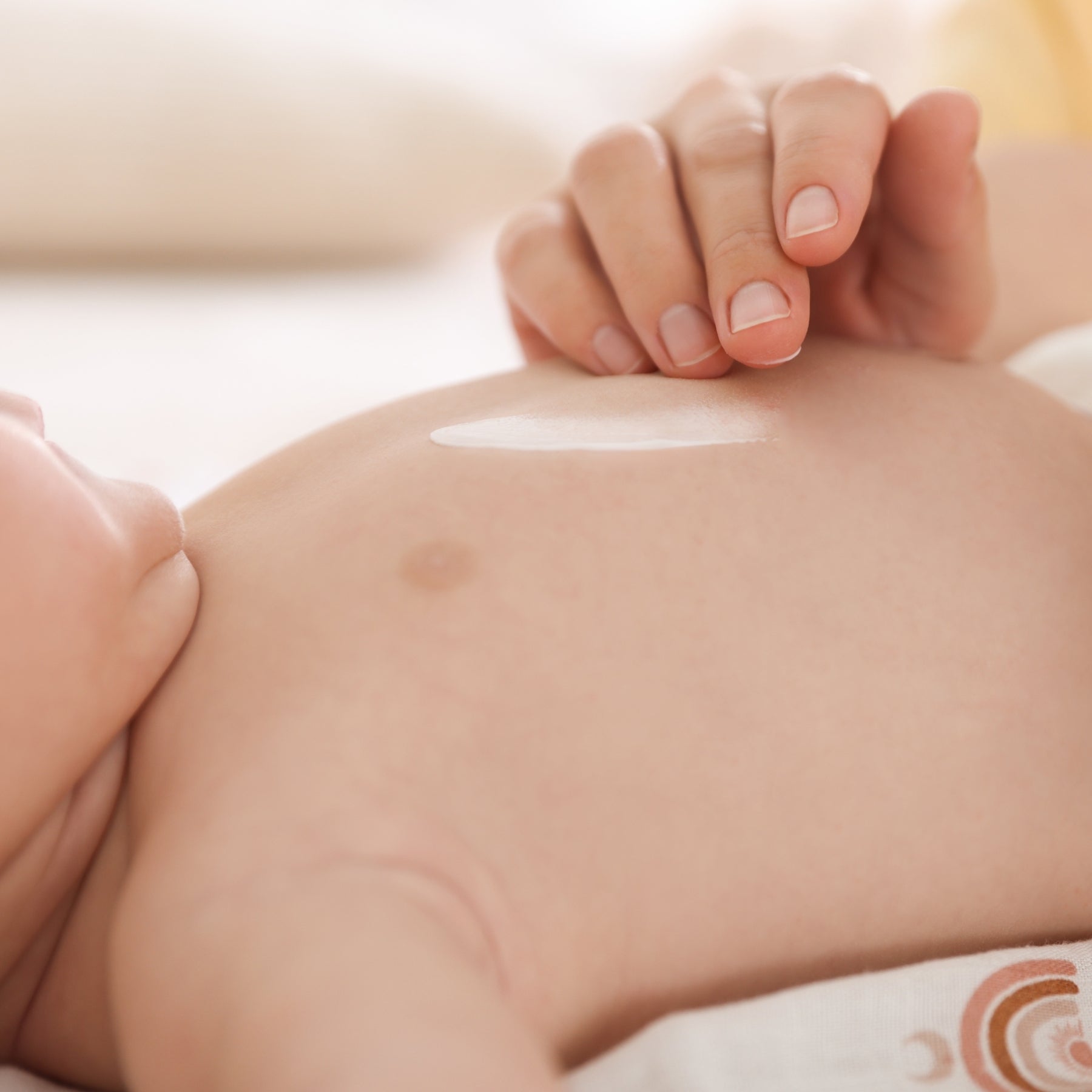 Mutterhand cremt sanft den Bauch eines Babys ein – zarte Babypflege mit der reinen Demeter Bio-Traubenkosmetik von dieNikolai, vegan und palmölfrei