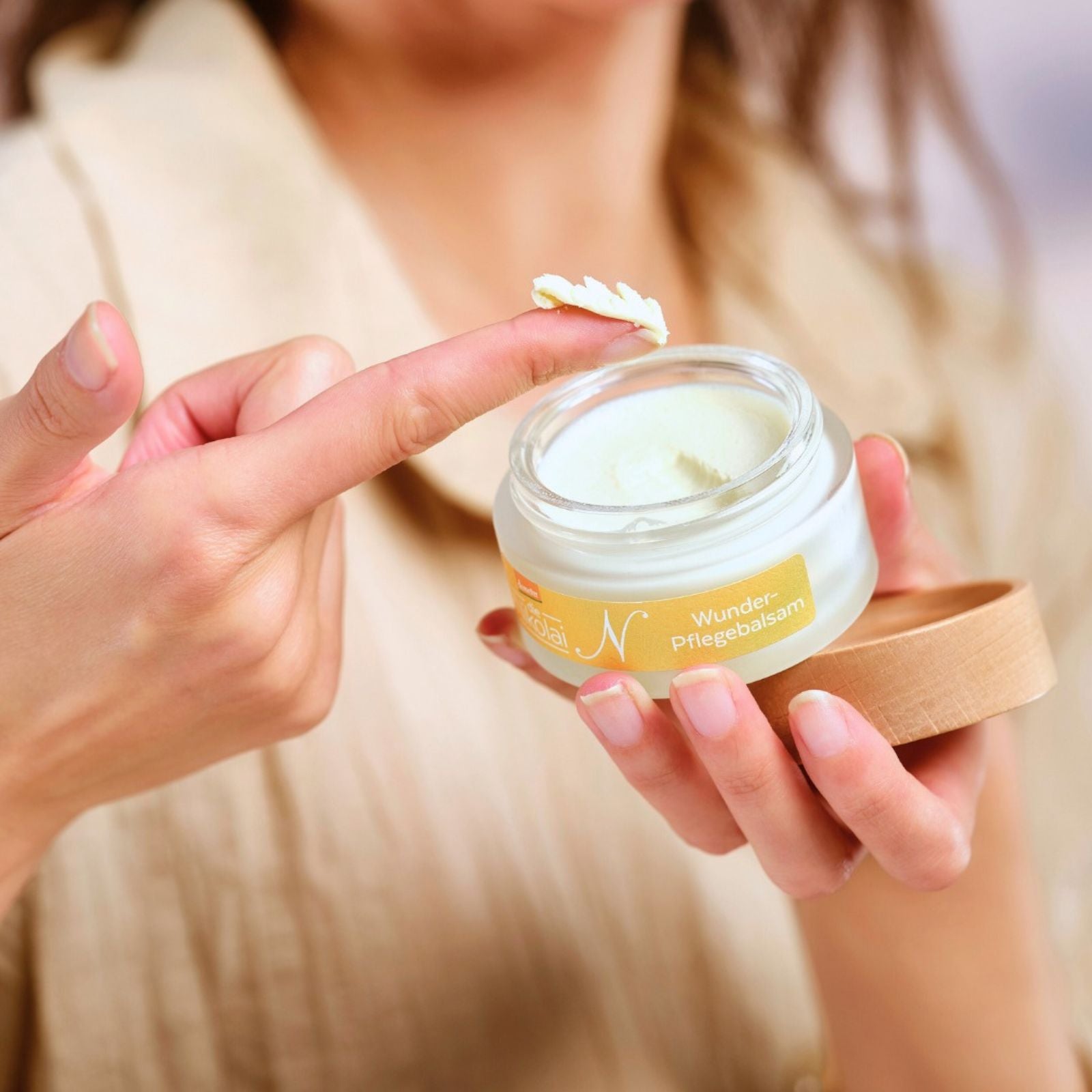 Frau entnimmt mit dem Finger Creme aus dem dieNikolai Wunder-Pflegebalsam im Tiegel – Demeter Bio-Traubenkosmetik mit Sheabutter aus der Wachau