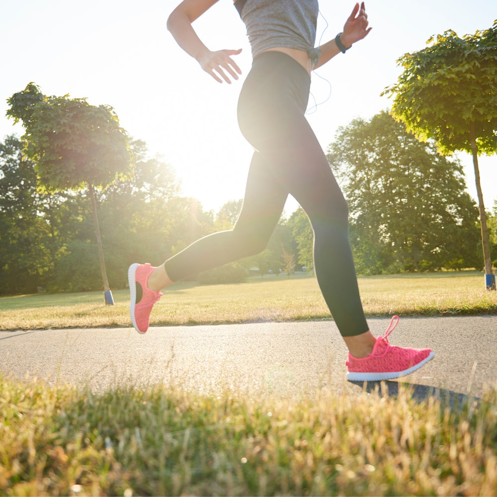 Joggerin mit pinken Laufschuhen läuft in der Morgensonne durch den Park – aktiver Lebensstil mit dieNikolai Bio-Traubenkosmetik und Nahrungsergänzung aus Österreich