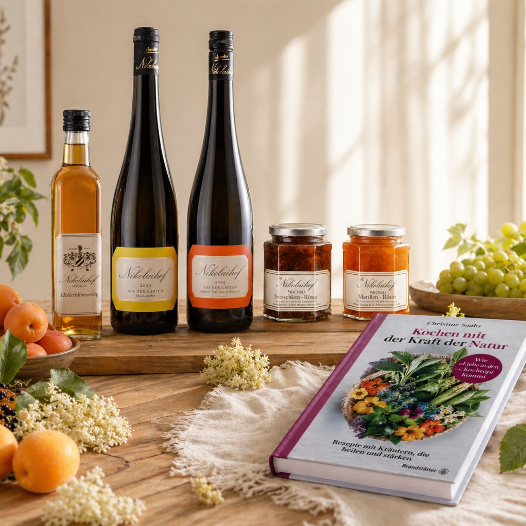 Geschenk-Arrangement mit Nikolaihof Wachau Wein, Hollerblütensirup, Marmeladen, Marillen und Kochbuch der Natur – Mitbringsel im dieNikolai Sortiment