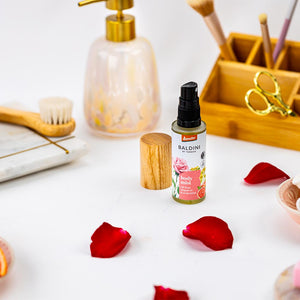 Baldini by Taoasis Body Mist mit Rose, Grapefruit und Lindenblüte als Demeter-Naturduft auf weißem Tisch mit Rosenblüten – erhältlich bei dieNikolai
