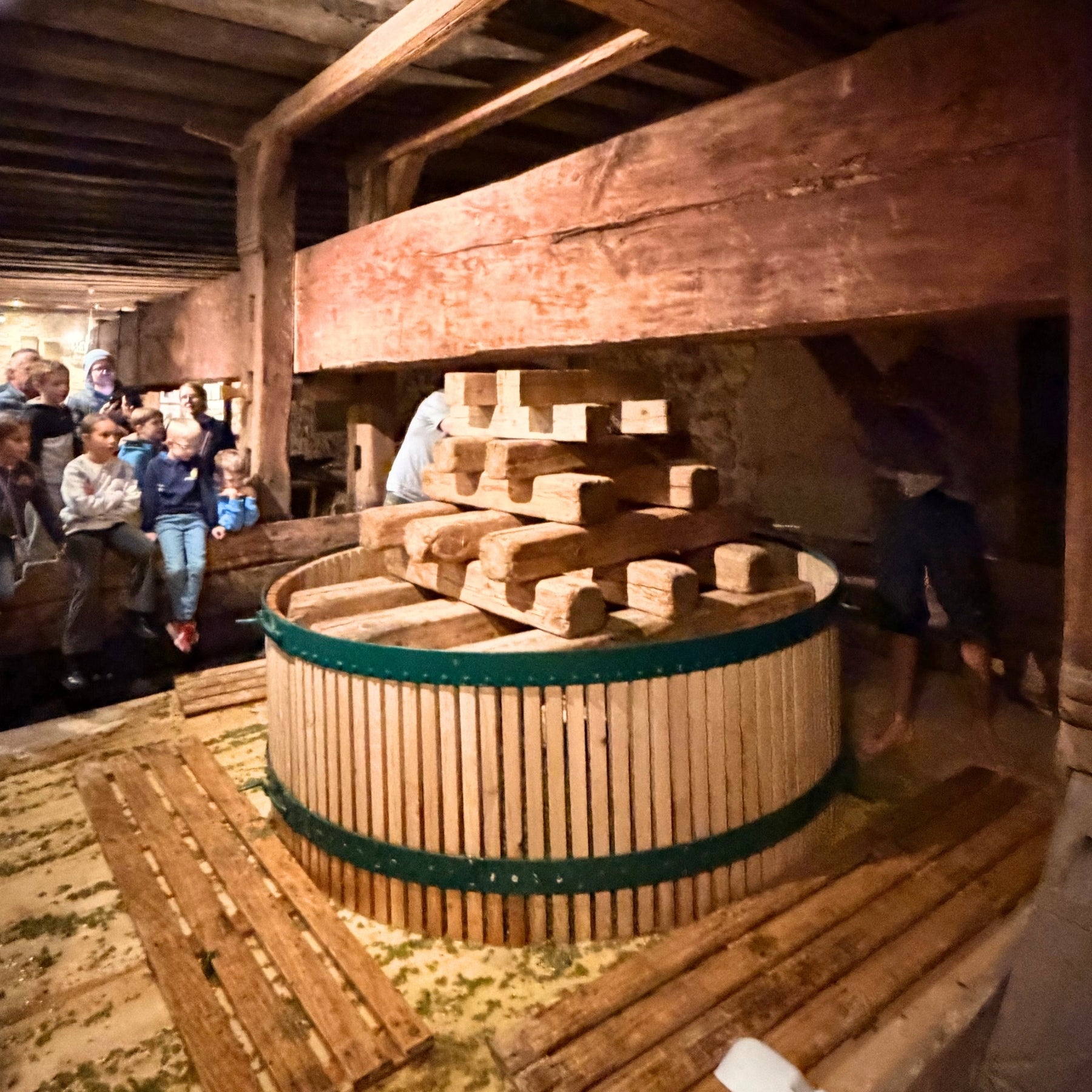 Historische Holzweinpresse im Nikolaihof Keller mit Kindergruppe – traditionelle Weinverarbeitung im Demeter-Weingut der dieNikolai Bio-Traubenkosmetik aus der Wachau