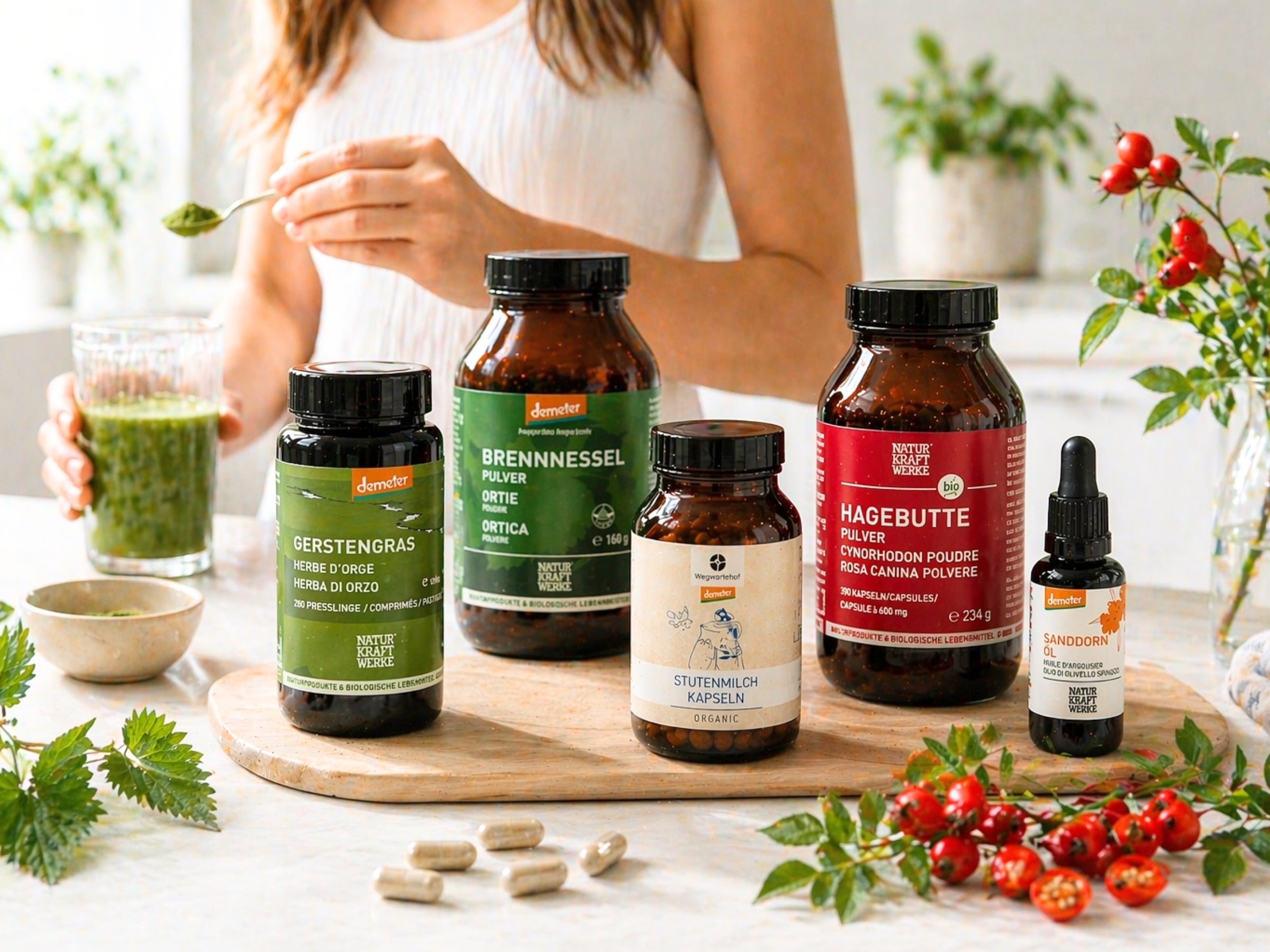 Frau am Tisch mit Green Smoothie und NaturKraftWerke Gerstengras, Brennnessel, Stutenmilch, Hagebutte und Sanddornöl – Nahrungsergänzung im dieNikolai Sortiment