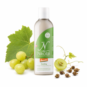dieNikolai Bio-Traubenkosmetik Riesling Duschgel, Shampoo und Shower Gel auf weißem Hintergrund, dezent dekoriert mit weißen Weintrauben, Weinblättern und Traubenkernen.